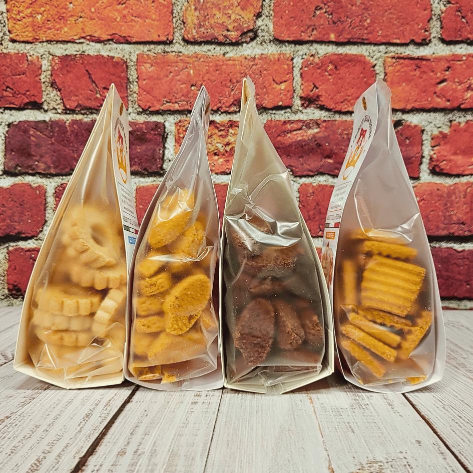 Quattro confezioni di biscotti artigianali di diversi tipi su fondo di mattoni rossi, C'era una volta - Bottega delle Mucche - Trecate (NO)
