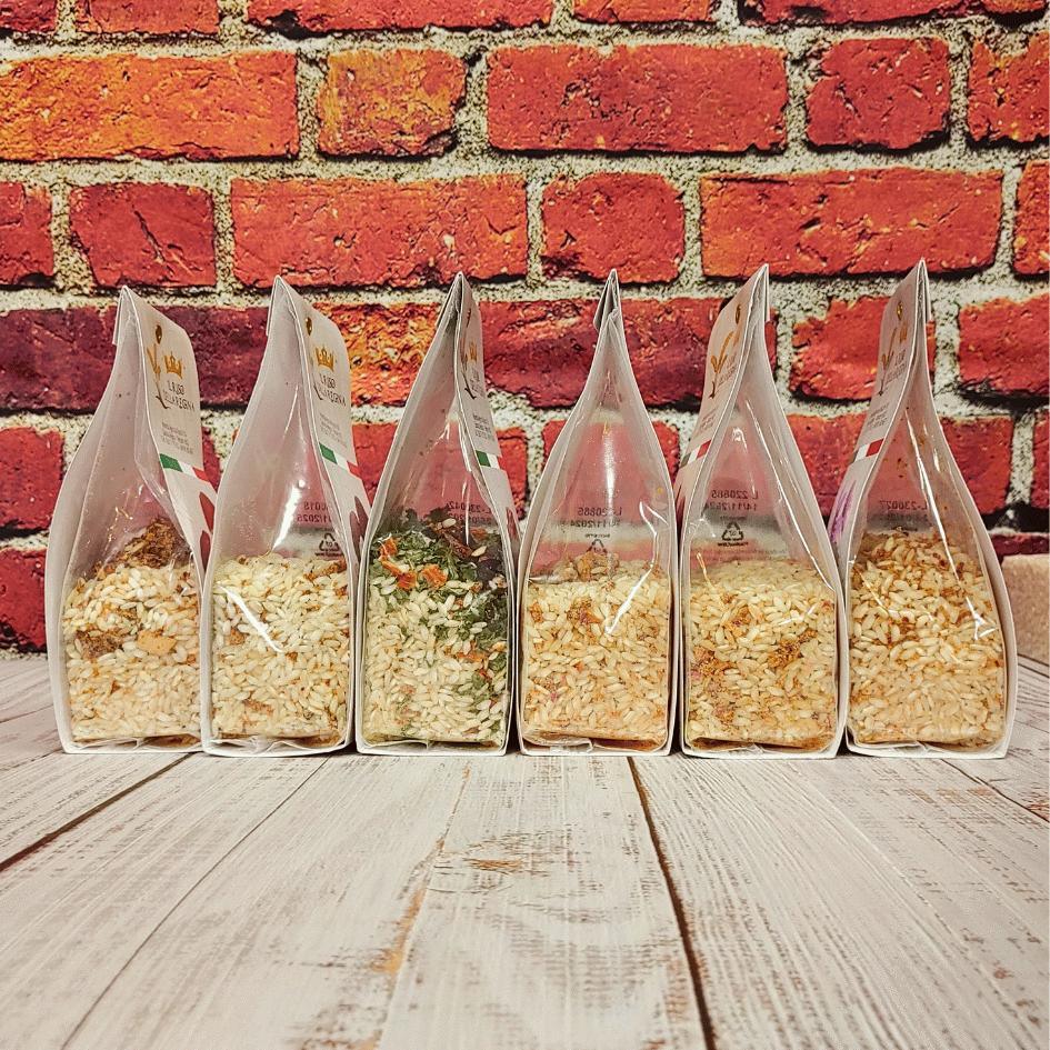 Sei confezioni di risotti gourmet con riso e spezie su tavola in legno, sfondo muro mattoni, C'era una volta - Bottega delle Mucche - Trecate (NO)